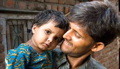 Parivartan participant Mohammed Amin Sheikh holds his youngest daughter outside of his small home in the Shivaji Nagar slum in Mumbai.  Mohammed says he is committed to the Parivartan project and is eager to mentor the young boys he coaches through cricket in issues of gender equality.