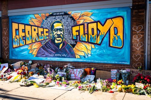 Mural of George Floyd with flowers placed on the floor beneath it.