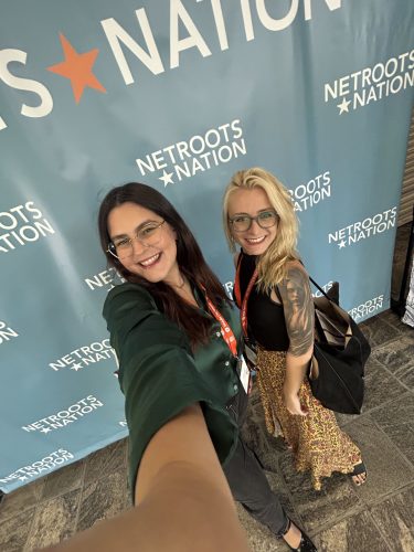 two people taking a selfie in front of a step and repeat backdrop