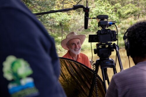 Farmer in Brazil sitting by water with video production equipment