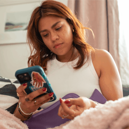 Individual holds pills in left hand and looks at phone in right hand