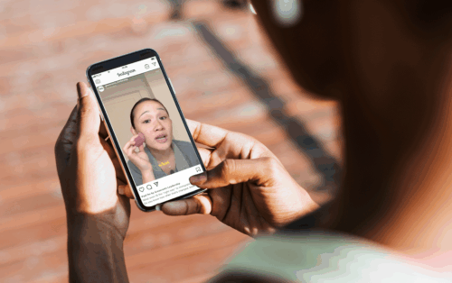 A woman looks at an influencer video on her phone.